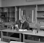 858511 Afbeelding van een jongeman met een weegschaal, vermoedelijk in een laboratorium van de N.S.